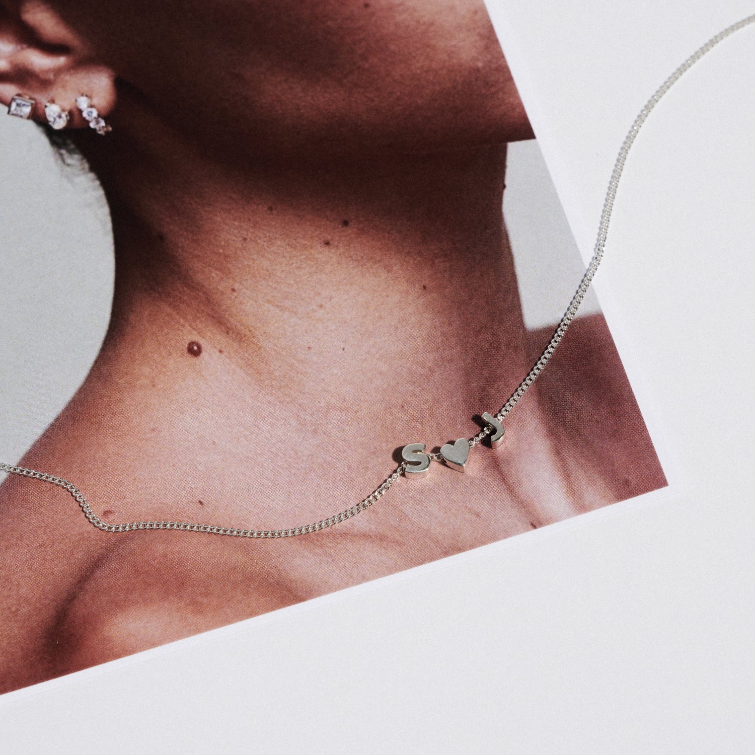 Close-up of a silver necklace with heart-shaped pendants on a neutral background