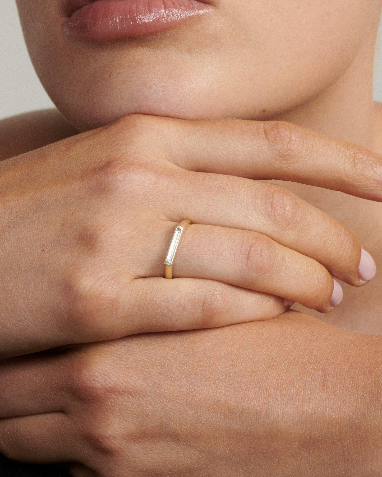Close-up of a hand wearing a gold ring with a white stone.