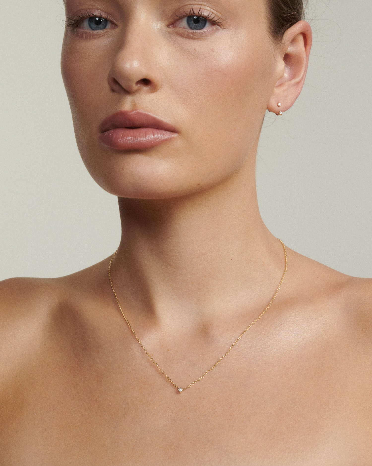 Model wears a gold chain with a tiny diamond fixed to the centre