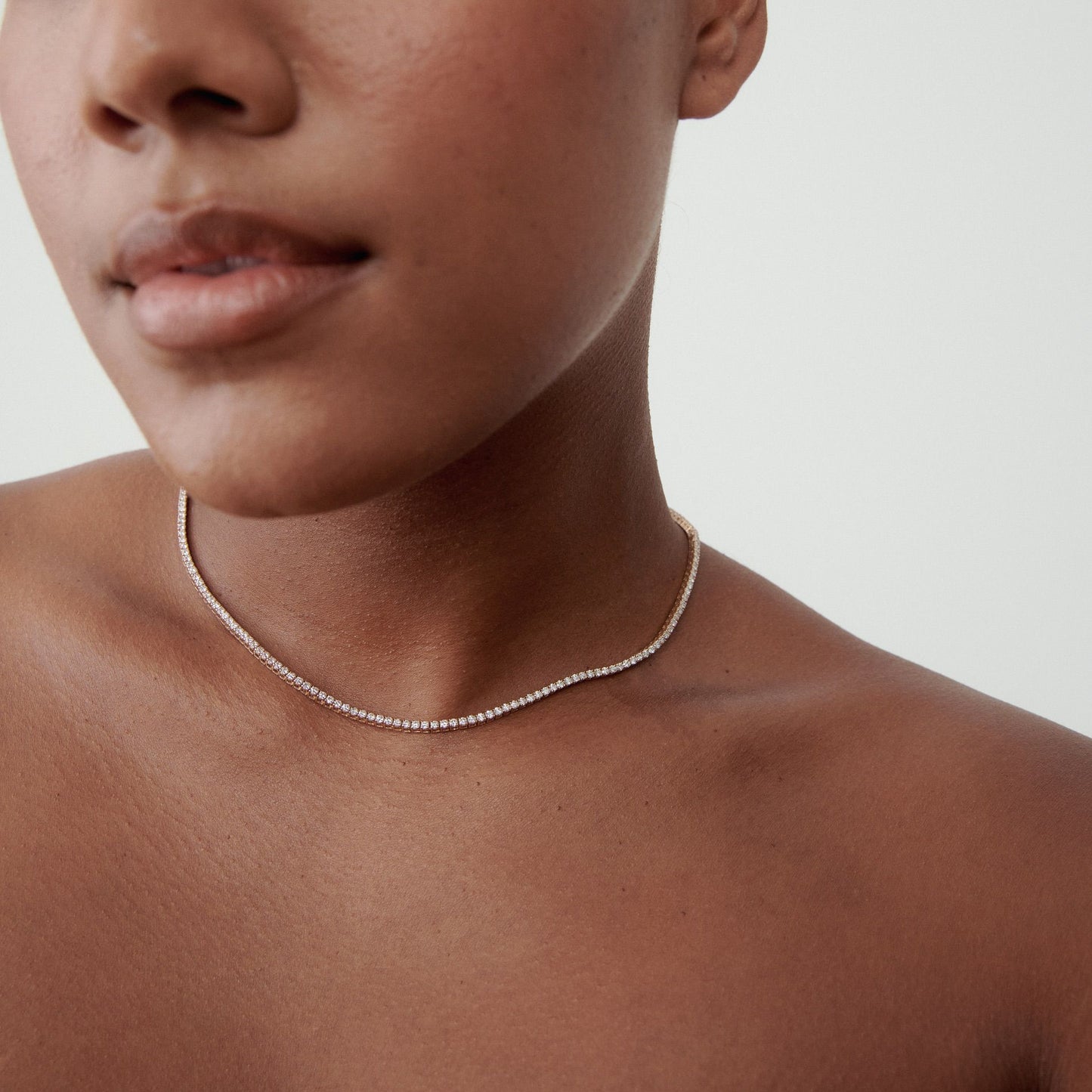 Close-up of a person wearing a delicate diamond choker necklace against bare skin, showcasing luxury jewellery.