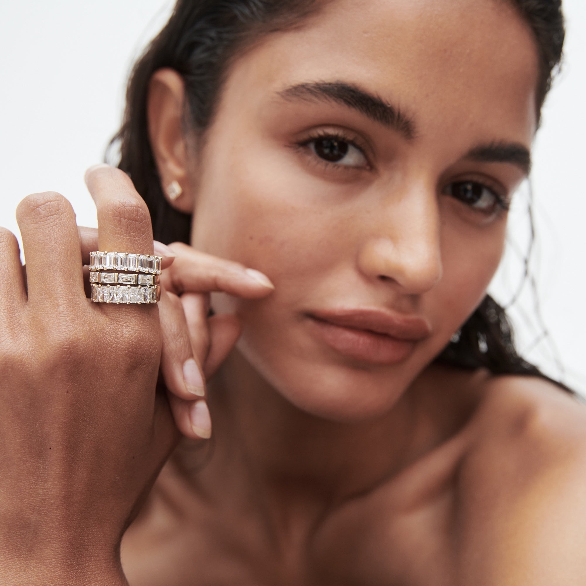 Woman wearing elegant, stacked diamond rings, posing with hand near face. Luxurious high-end jewellery, sophisticated style close-up.