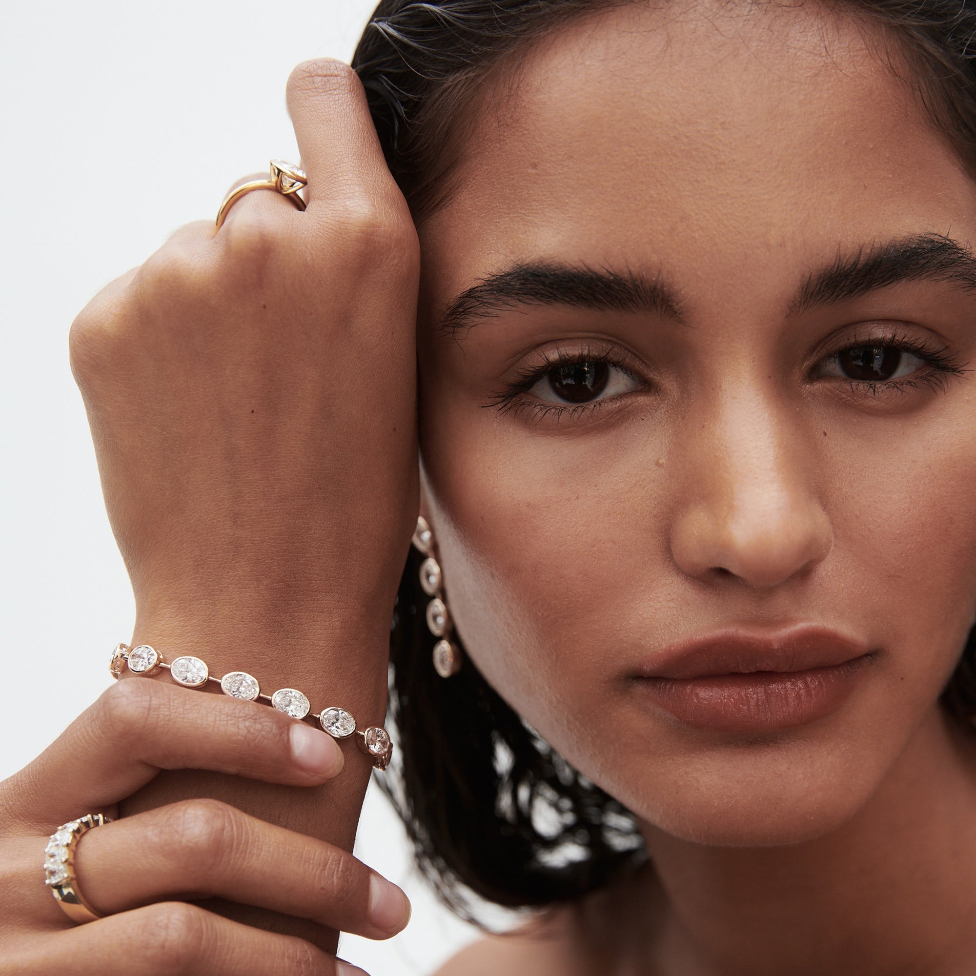 Woman showcasing luxury jewellery: diamond bracelet, ring, and earrings. Sophisticated style, high-end fashion focus.