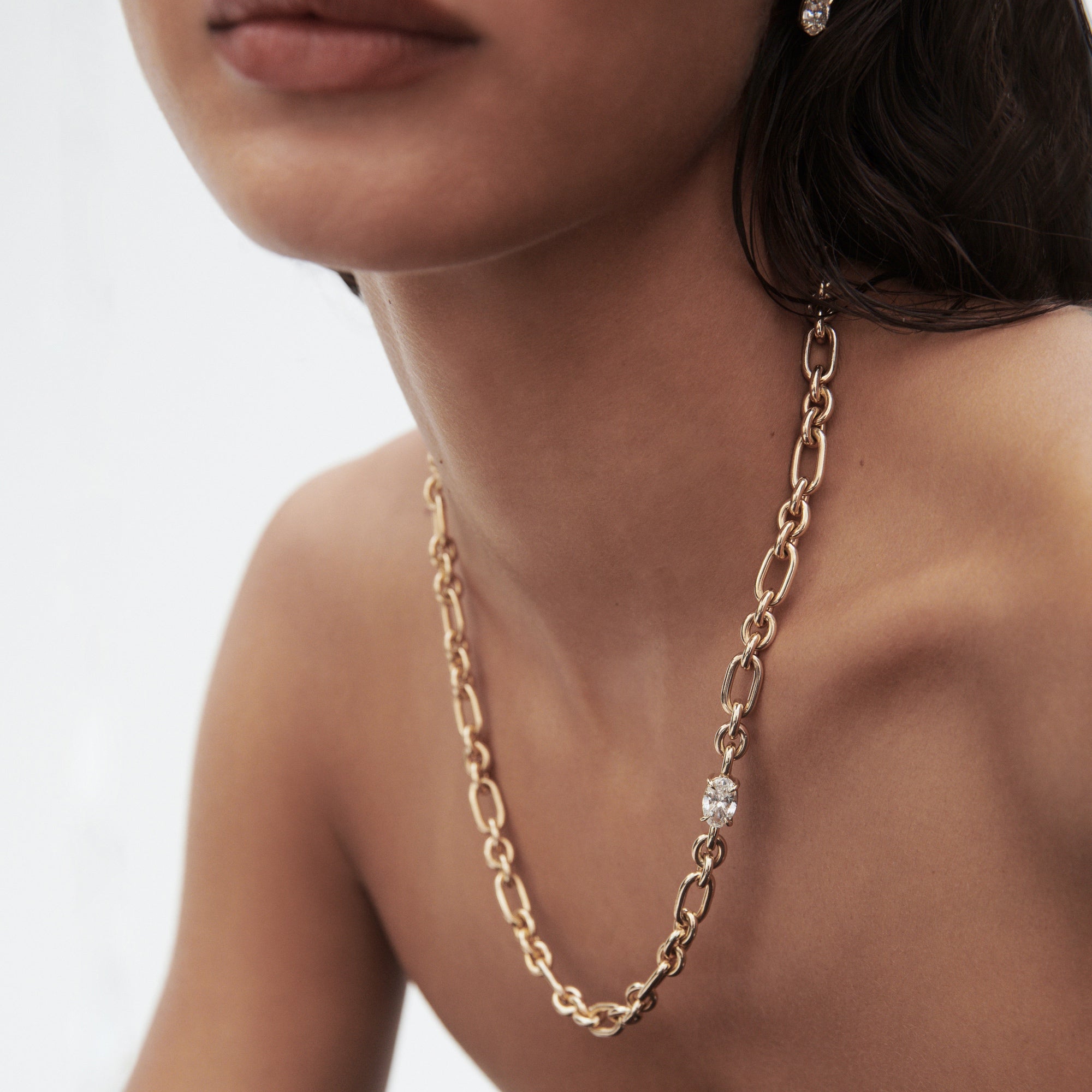 Woman wearing a luxury gold chain necklace with a diamond accent, showcasing elegance. Perfect for high-end jewellery enthusiasts.