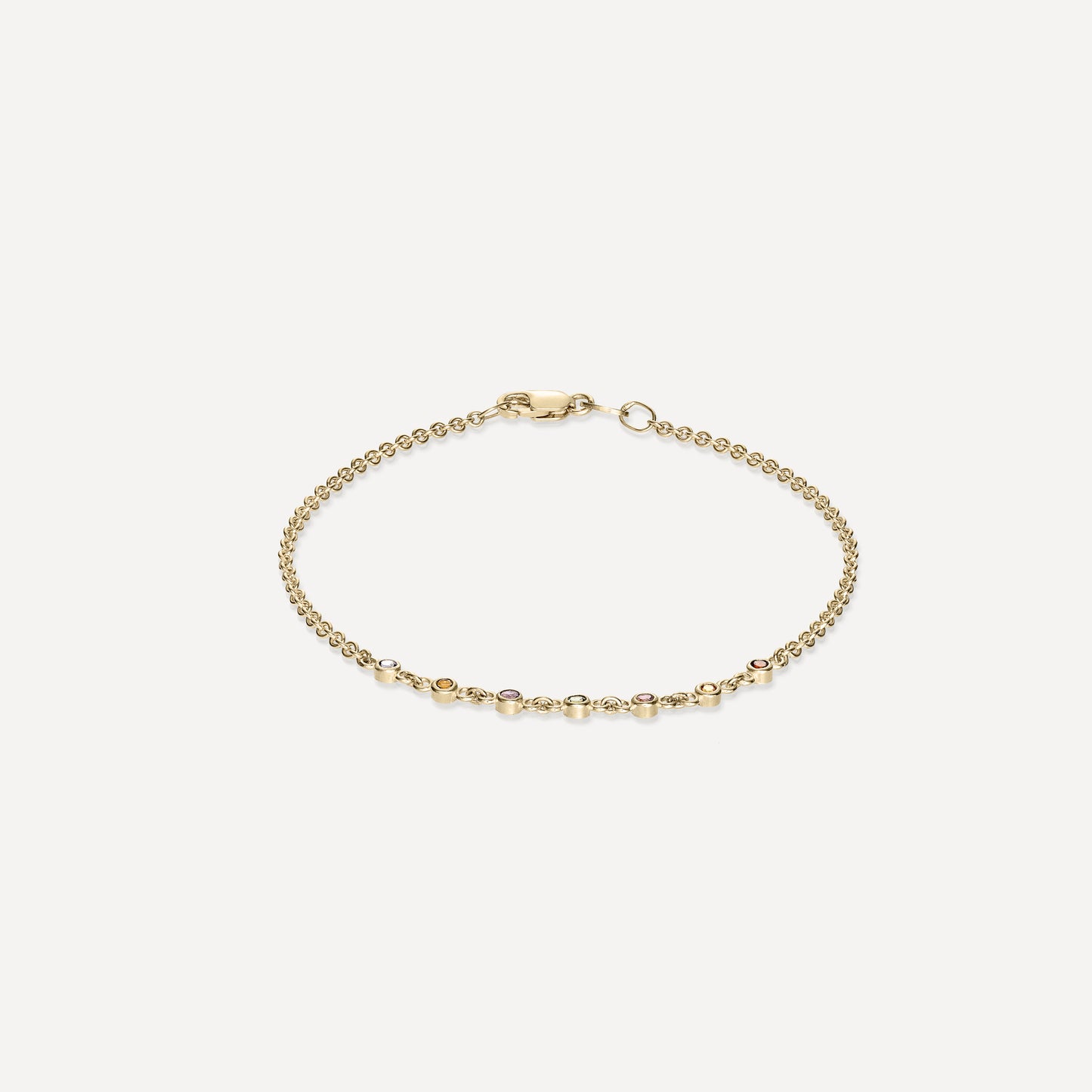 Gold chain bracelet with round diamond accents set apart, featuring a secure clasp, showcased on a plain, light background.