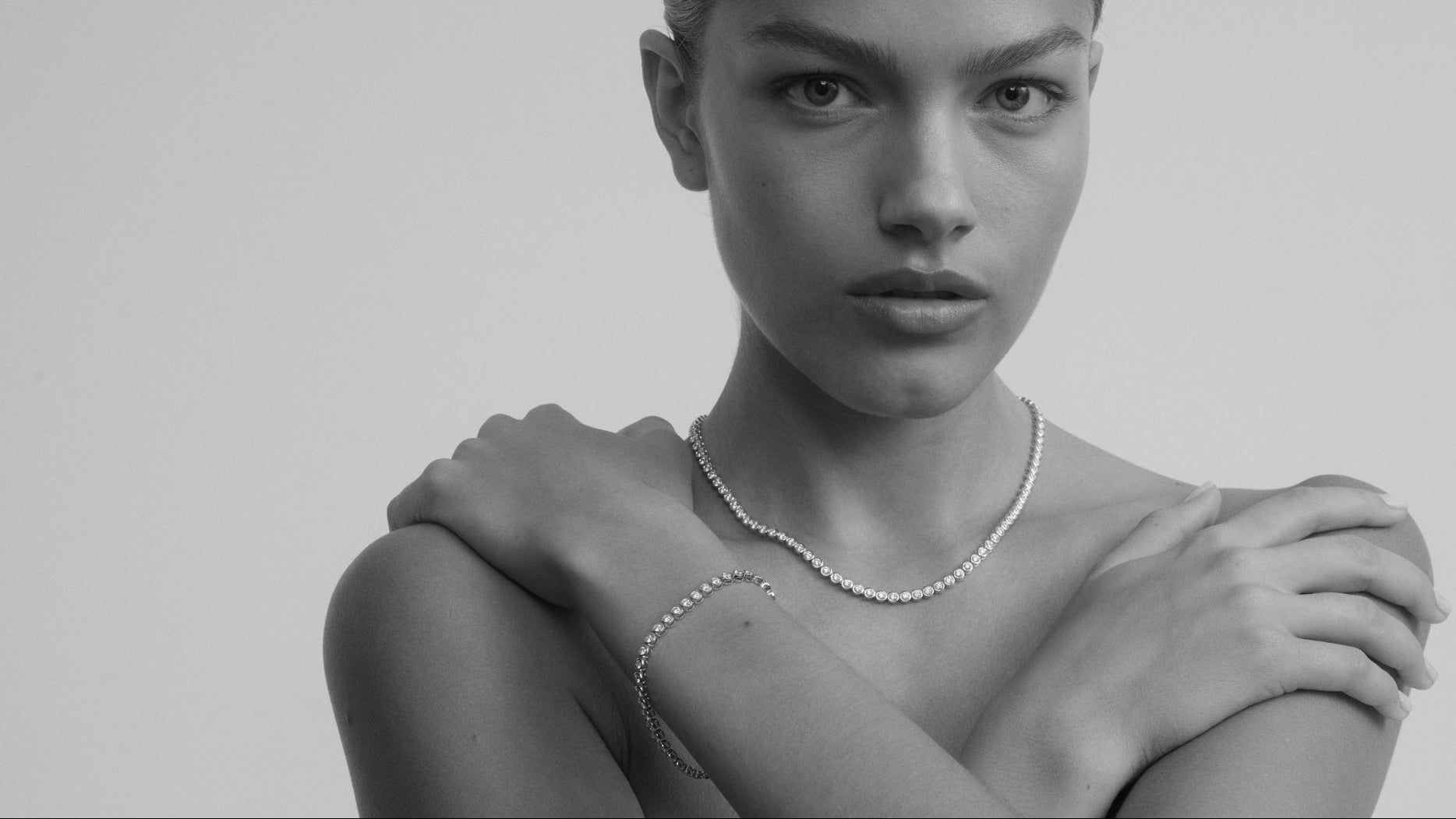 Black and white portrait of a woman wearing a pearl necklace with a plain background