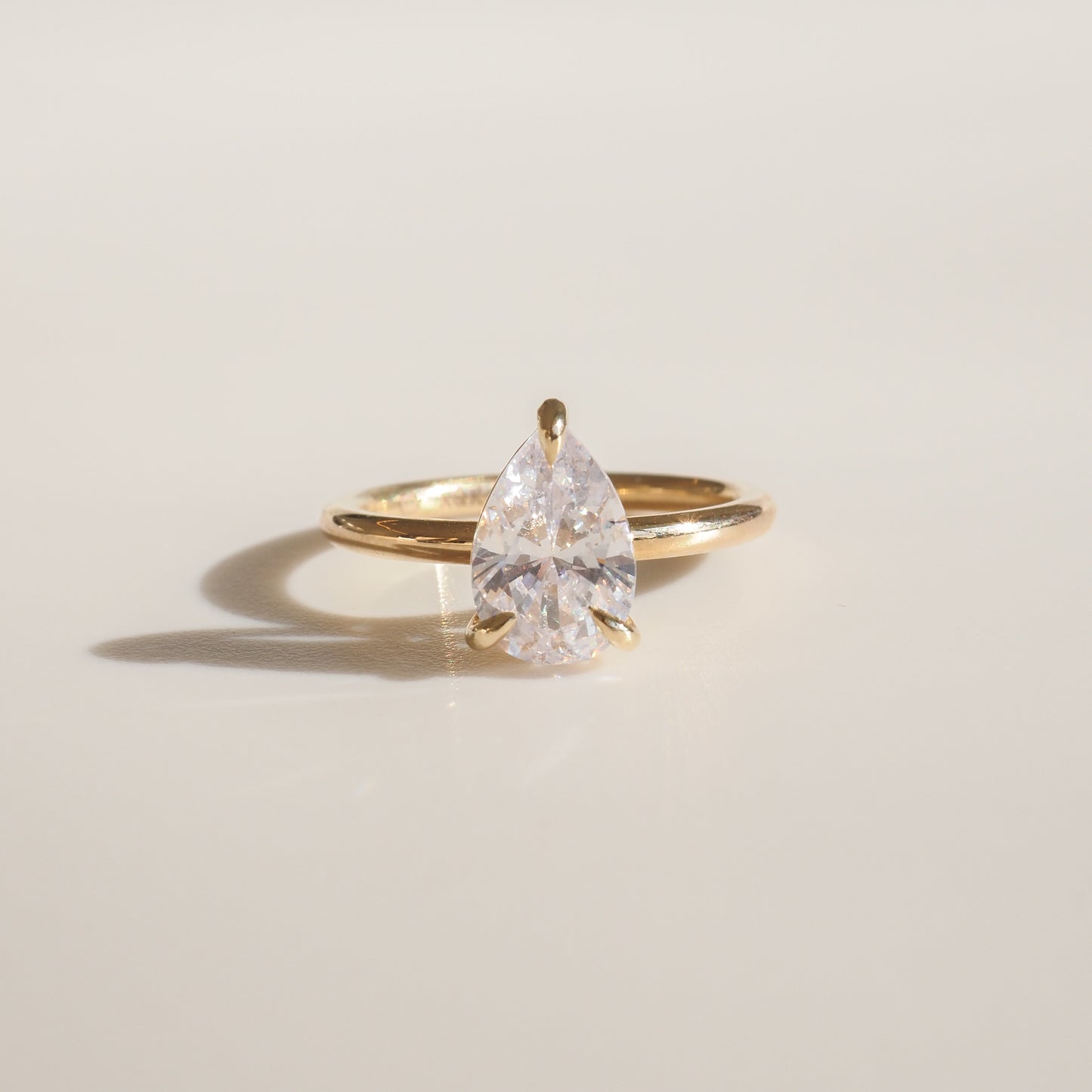 Gold ring with a large pear-shaped diamond, elegantly showcased on a light surface. Perfect for luxury jewellery enthusiasts.