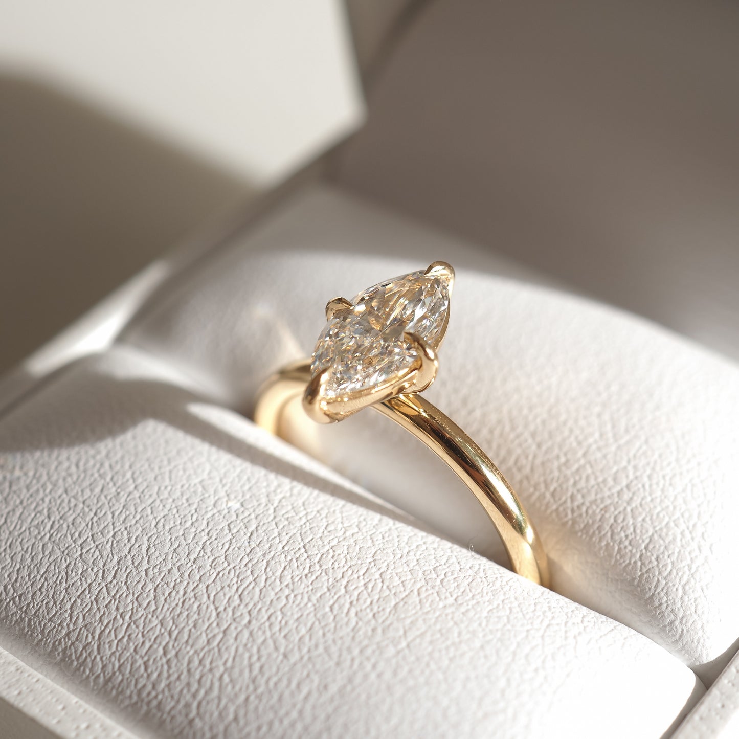 Gold ring with a marquise-cut diamond, elegantly presented in a white jewellery box. Perfect for luxury engagements or high-end fashion.