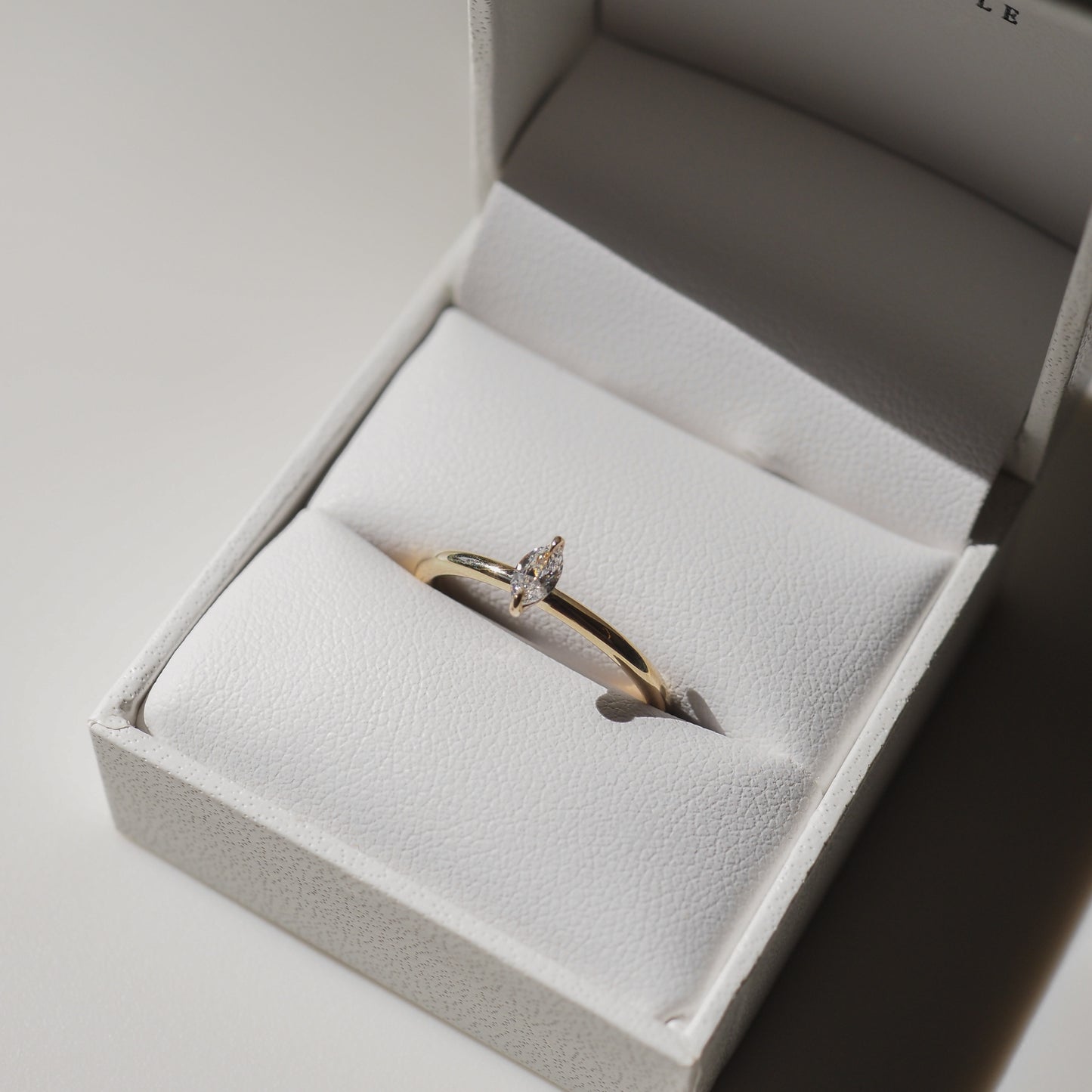 Gold ring with a marquise-cut diamond displayed in a white jewellery box, highlighting luxury and elegance in high-end jewellery design.