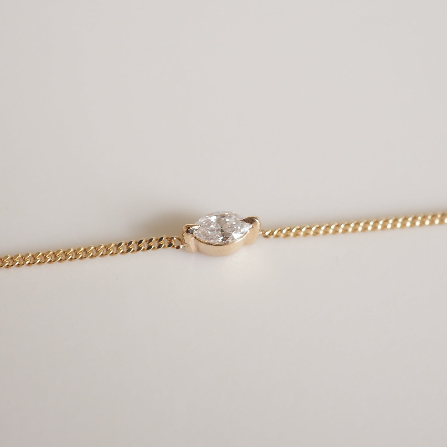 Gold bracelet featuring a marquise-cut diamond in a minimalist setting, symbolising luxury and elegance.