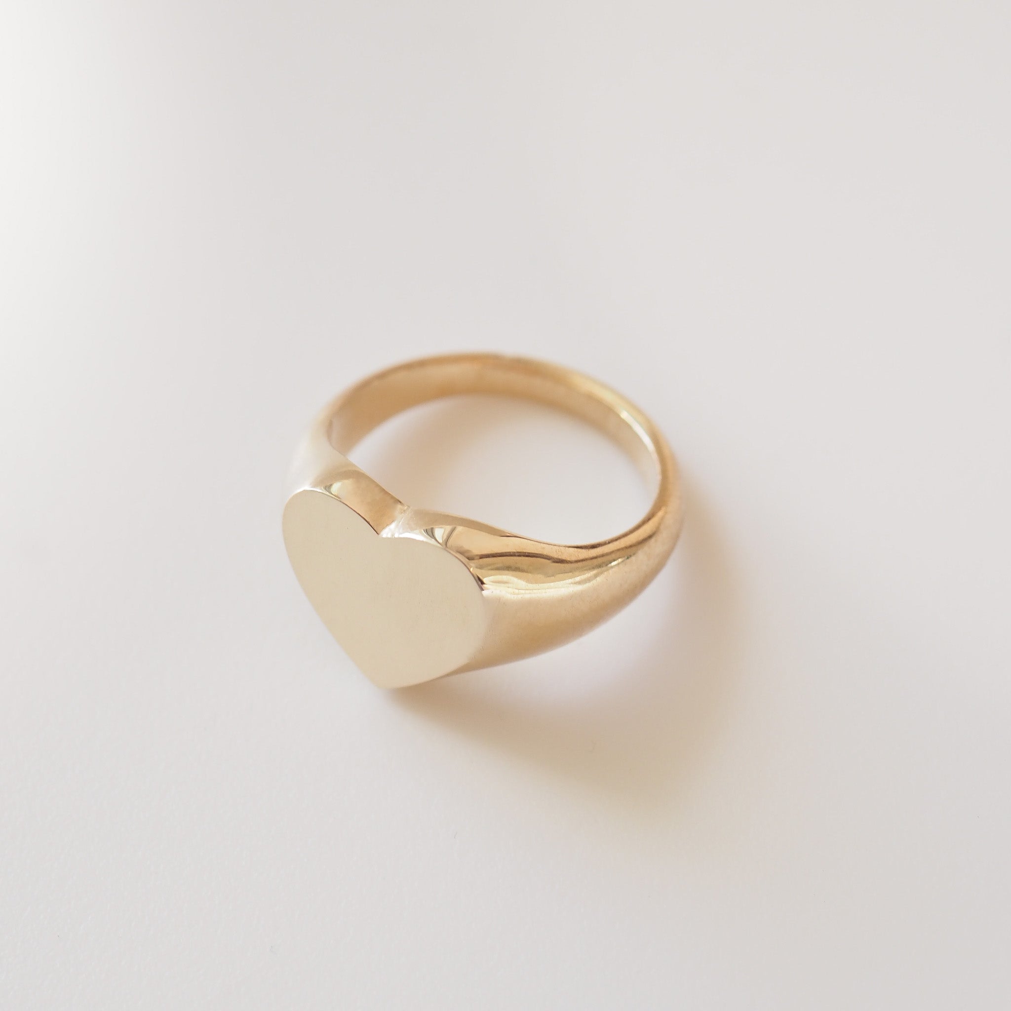 Gold ring with a heart-shaped design on a light gray background
