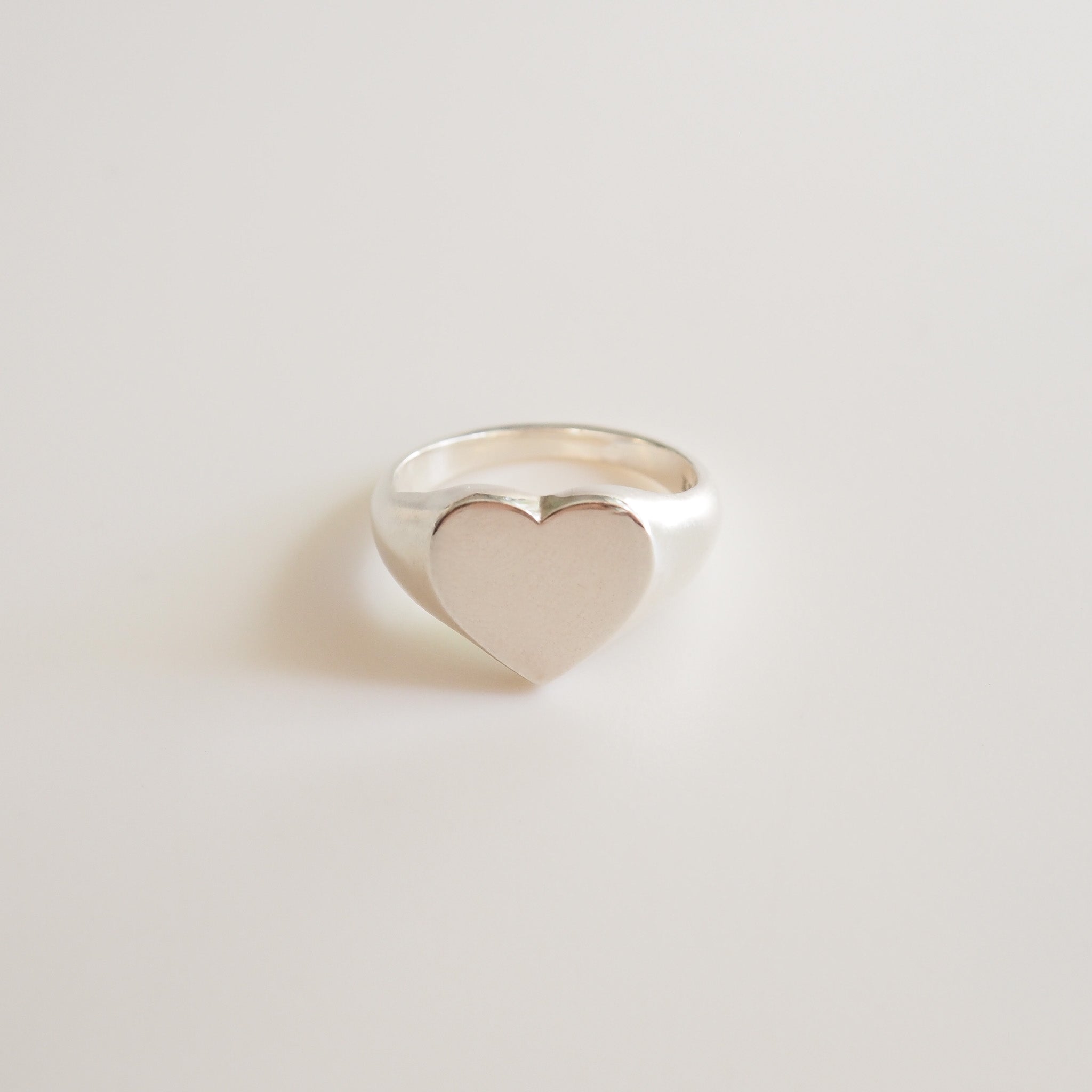 Heart-shaped silver ring on a light gray background
