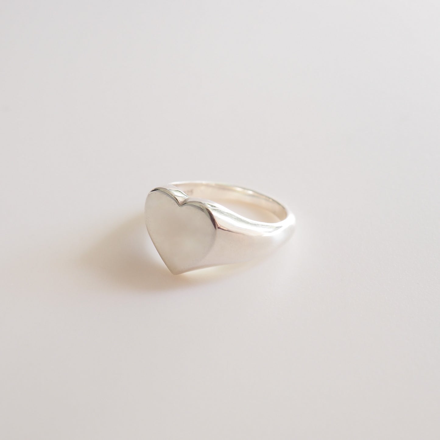 Silver heart-shaped ring on a light gray background