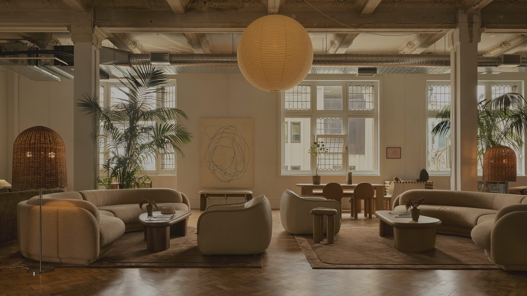 Modern interior design of a living room with beige sofas, wooden floors, and large windows.