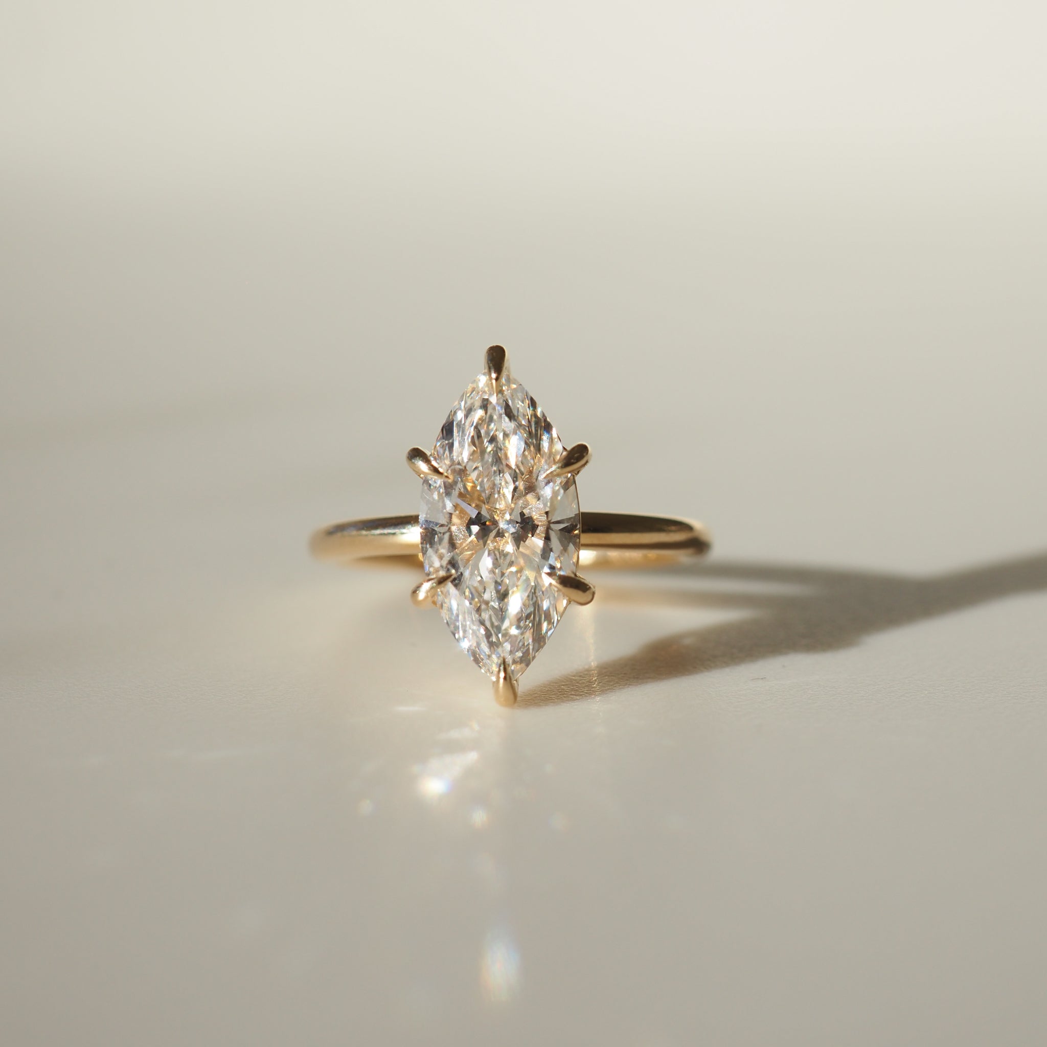 Marquise-cut diamond ring set on a sleek gold band, elegantly lit, displaying luxury jewellery craftsmanship.