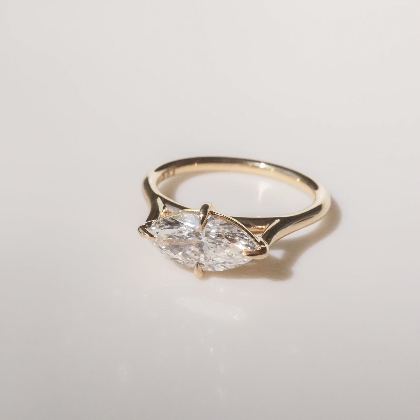 Gold ring with a marquise-cut diamond on a smooth, light background. Elegant and minimalist design, ideal for luxury jewellery lovers.