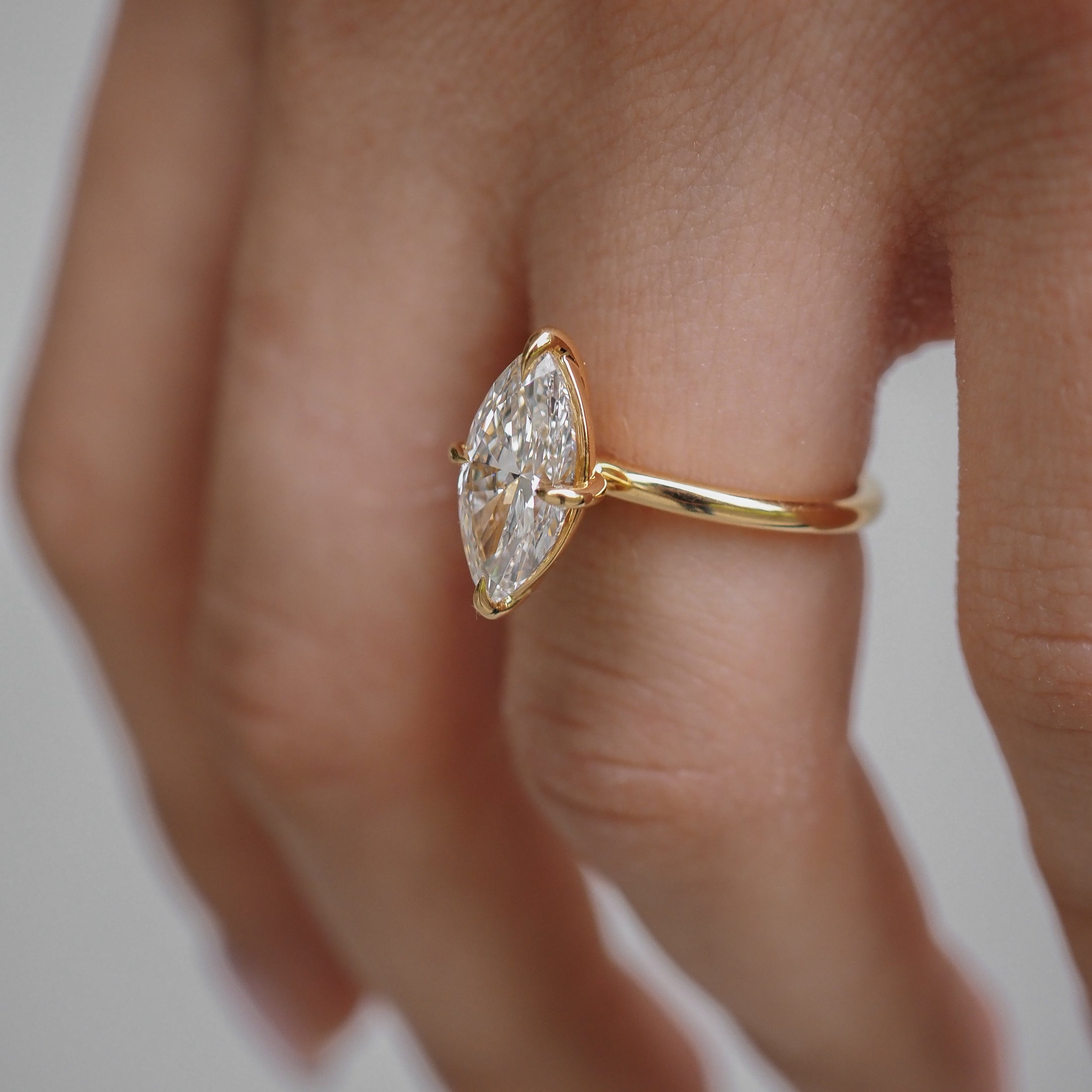 Close-up of a hand wearing a gold ring with a marquise-cut diamond. Elegant design highlights luxury jewellery craftsmanship.