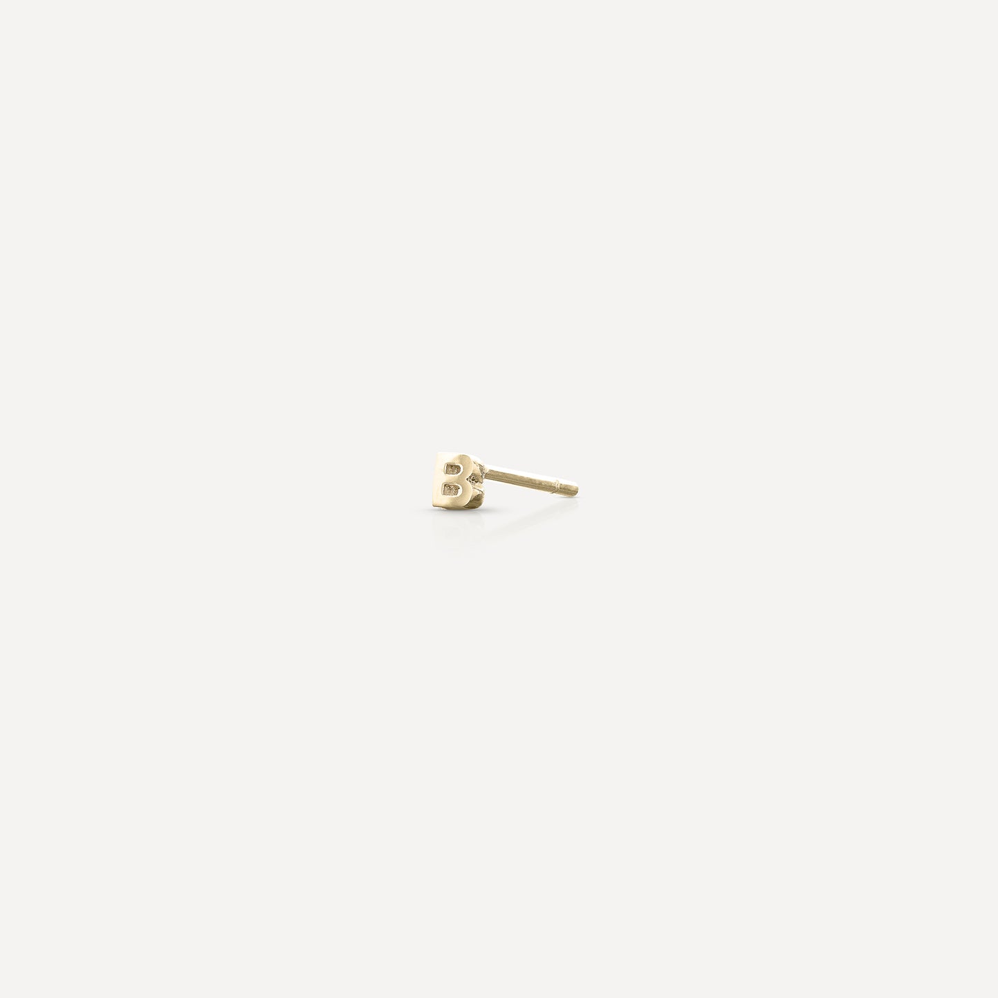 Gold letter 'B' stud earring on a white background, showcasing minimalist luxury jewellery design.