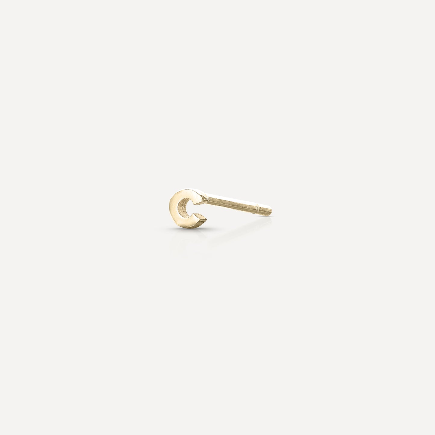 Minimalist gold earring stud on a light background; perfect for luxury fashion and jewellery enthusiasts seeking elegance and style.
