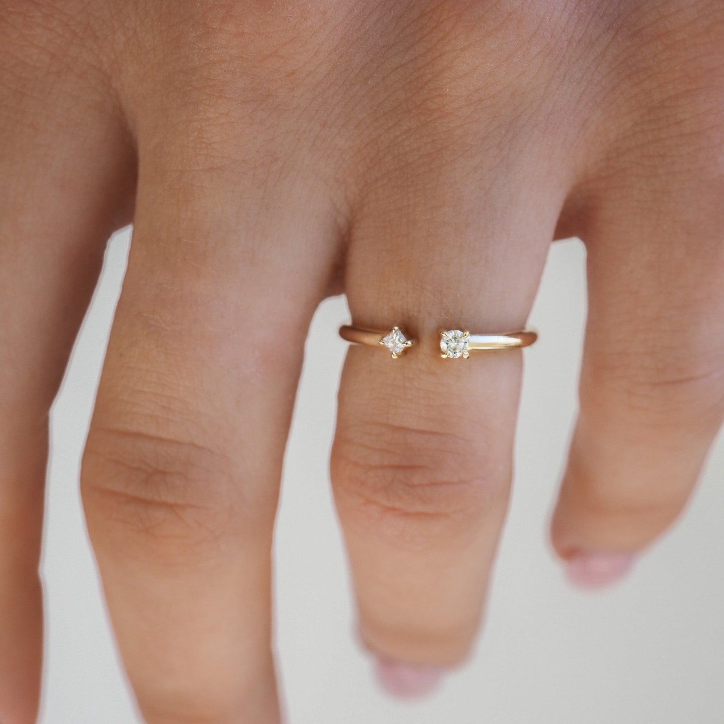 Gold open ring with two diamond settings on a hand. Fine jewellery, elegant minimalist design. Ideal for luxury accessory collections.