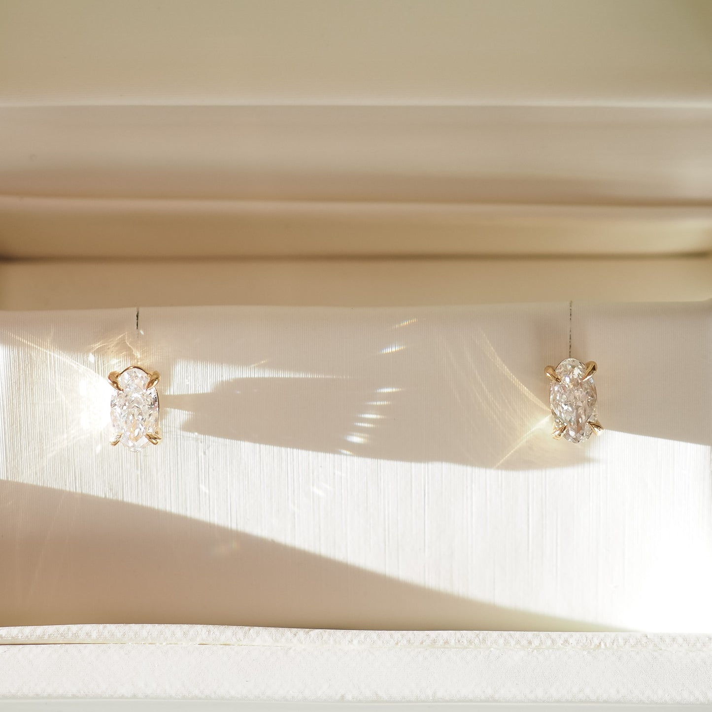 Pair of moval studs with clear gemstones on a neutral background