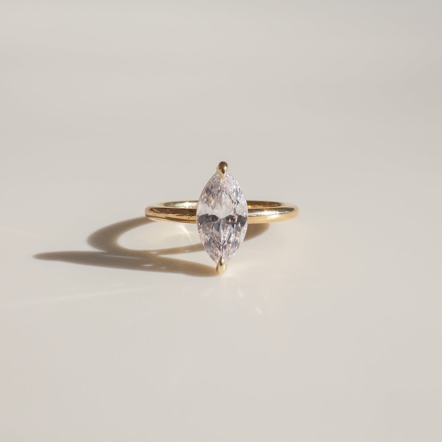 Elegant marquise diamond ring set in a slim gold band on a light surface, highlighting luxury jewellery design.