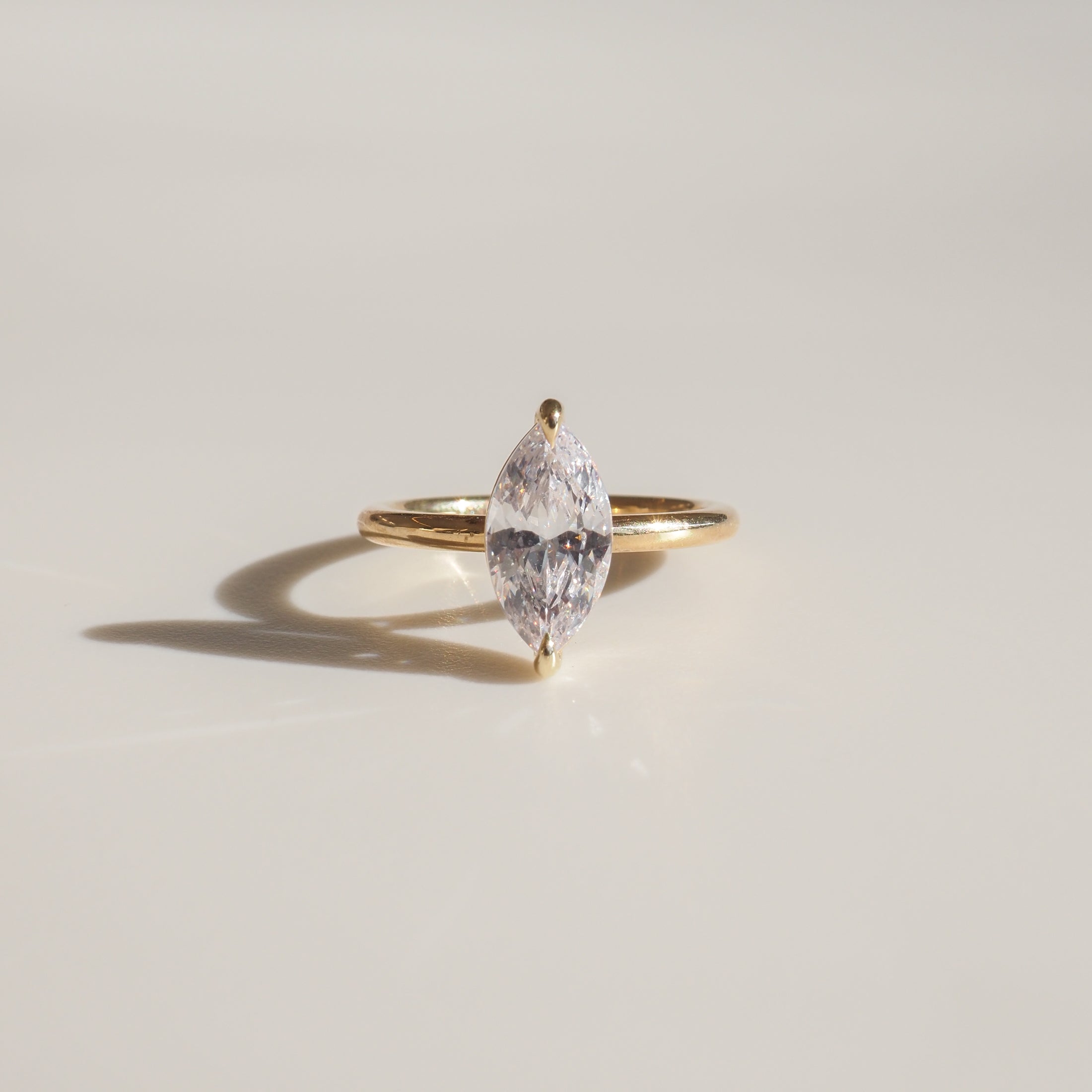 Elegant marquise diamond ring set in a slim gold band on a light surface, highlighting luxury jewellery design.