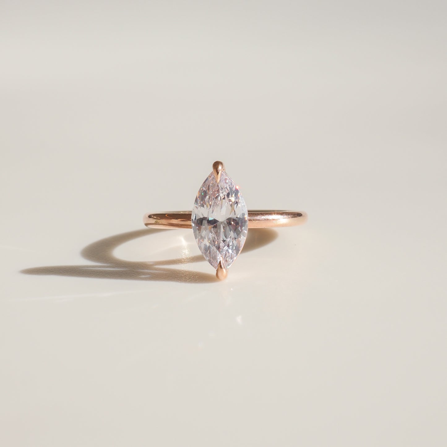 Marquise-cut diamond ring with a simple gold band, elegantly displayed on a light background, showcasing luxury jewellery craftsmanship.