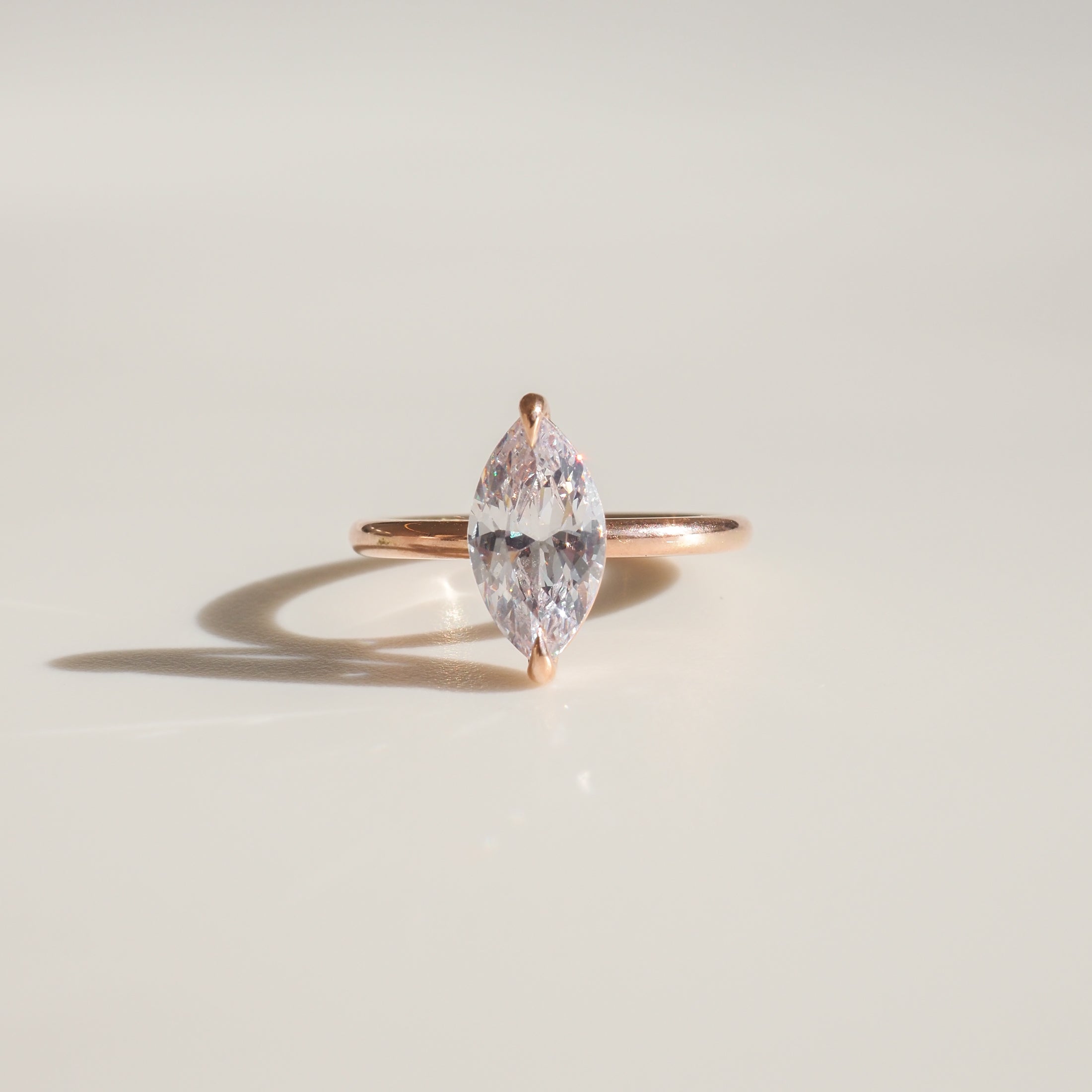 Marquise-cut diamond ring with a simple gold band, elegantly displayed on a light background, showcasing luxury jewellery craftsmanship.