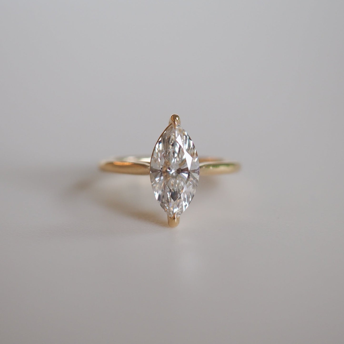 Marquise-cut diamond ring with a gold band on a neutral background; elegant luxury jewellery design.