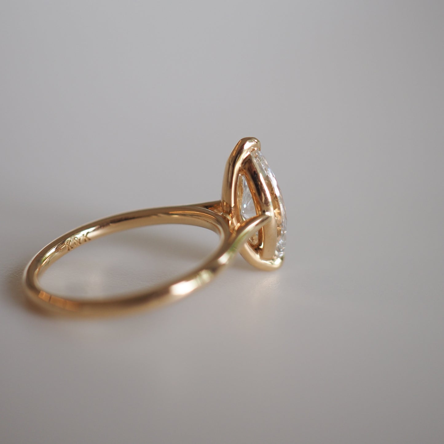 Gold engagement ring with marquise-cut diamond set sideways, showcasing minimalist elegance and luxury jewellery design.