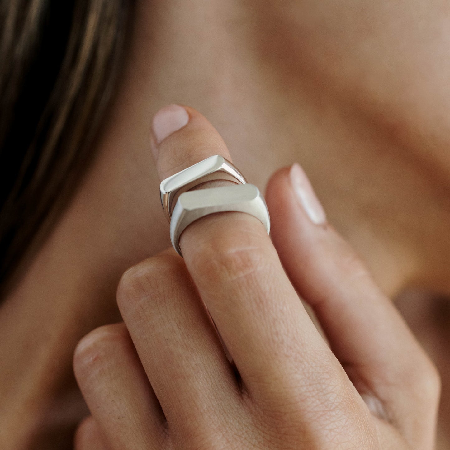 Close-up of a woman's hand wearing two modern silver rings on the index finger, showcasing luxury jewellery fashion.