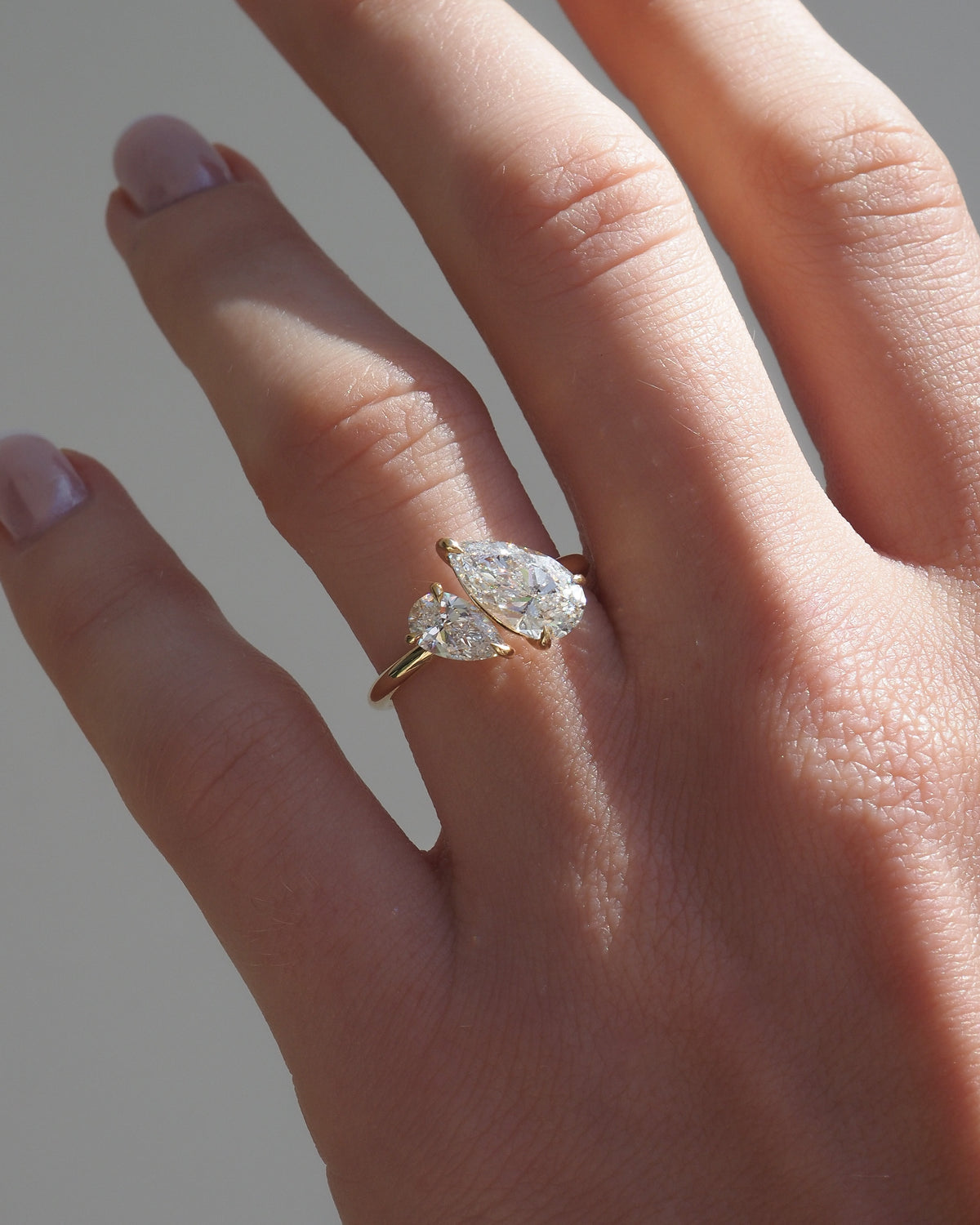 Gold engagement ring with two marquise lab-grown diamond stones on finger