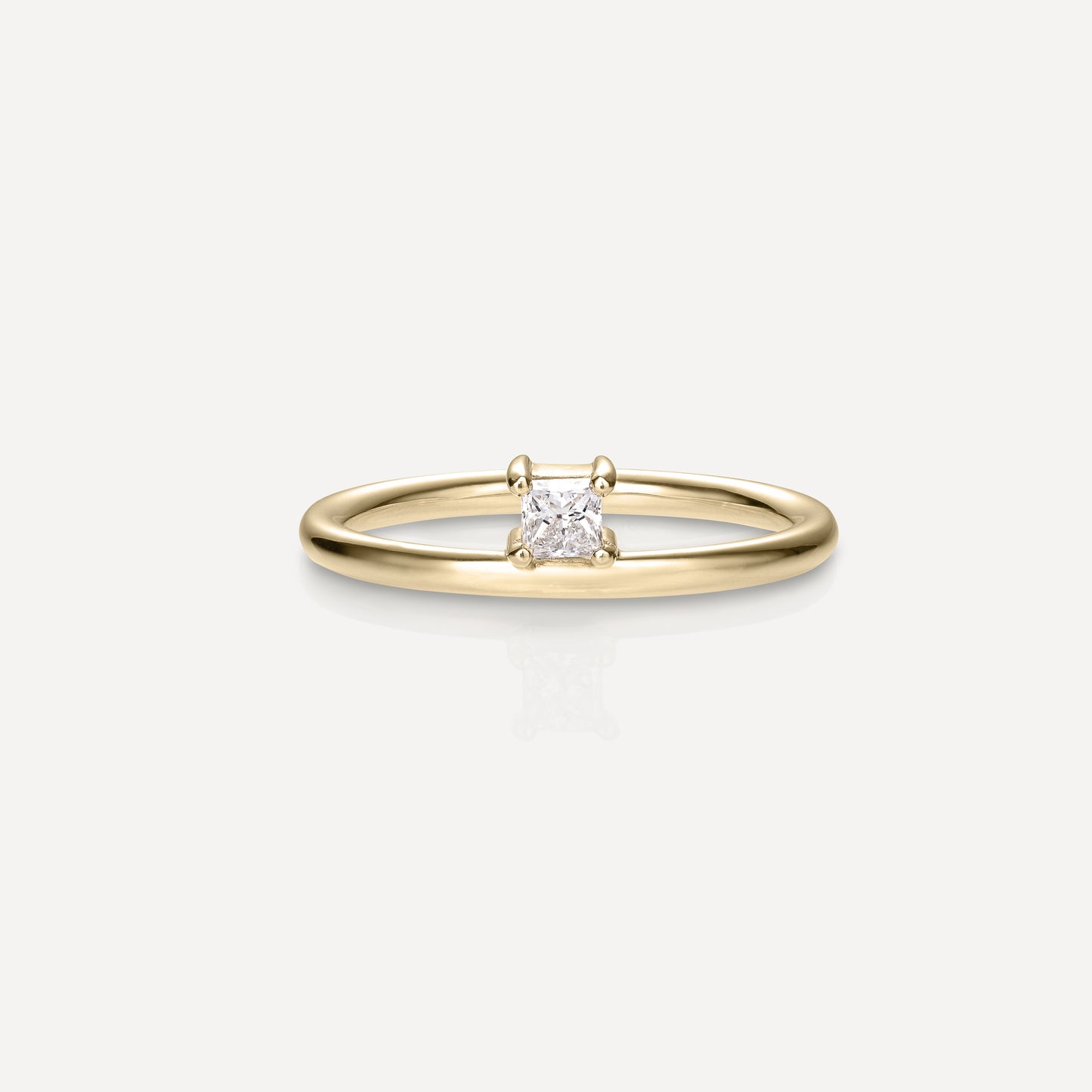 Gold solitaire ring featuring a radiant square diamond, set on a sleek band against a white background. Luxurious minimalist jewellery.