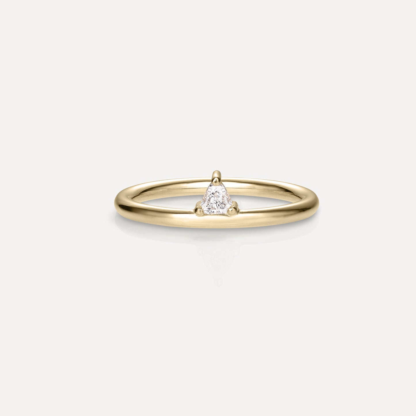 Gold ring with a delicate band featuring a small, central triangle-shaped diamond, set in minimalist prongs, on a light background.