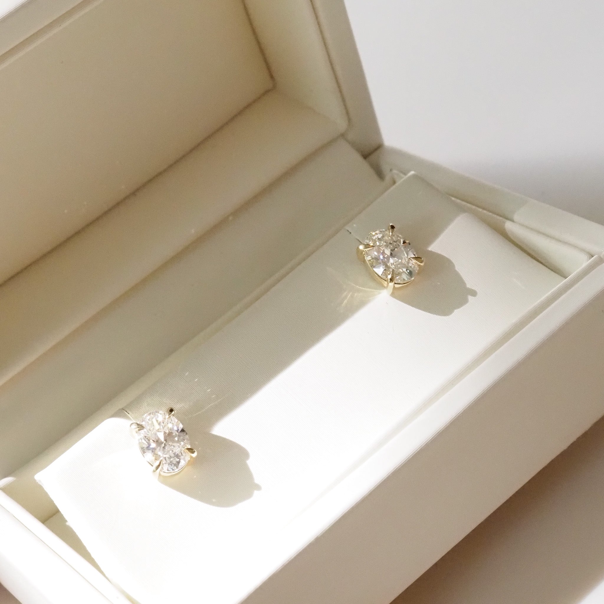 Oval Diamond studs in a cream box on a white background