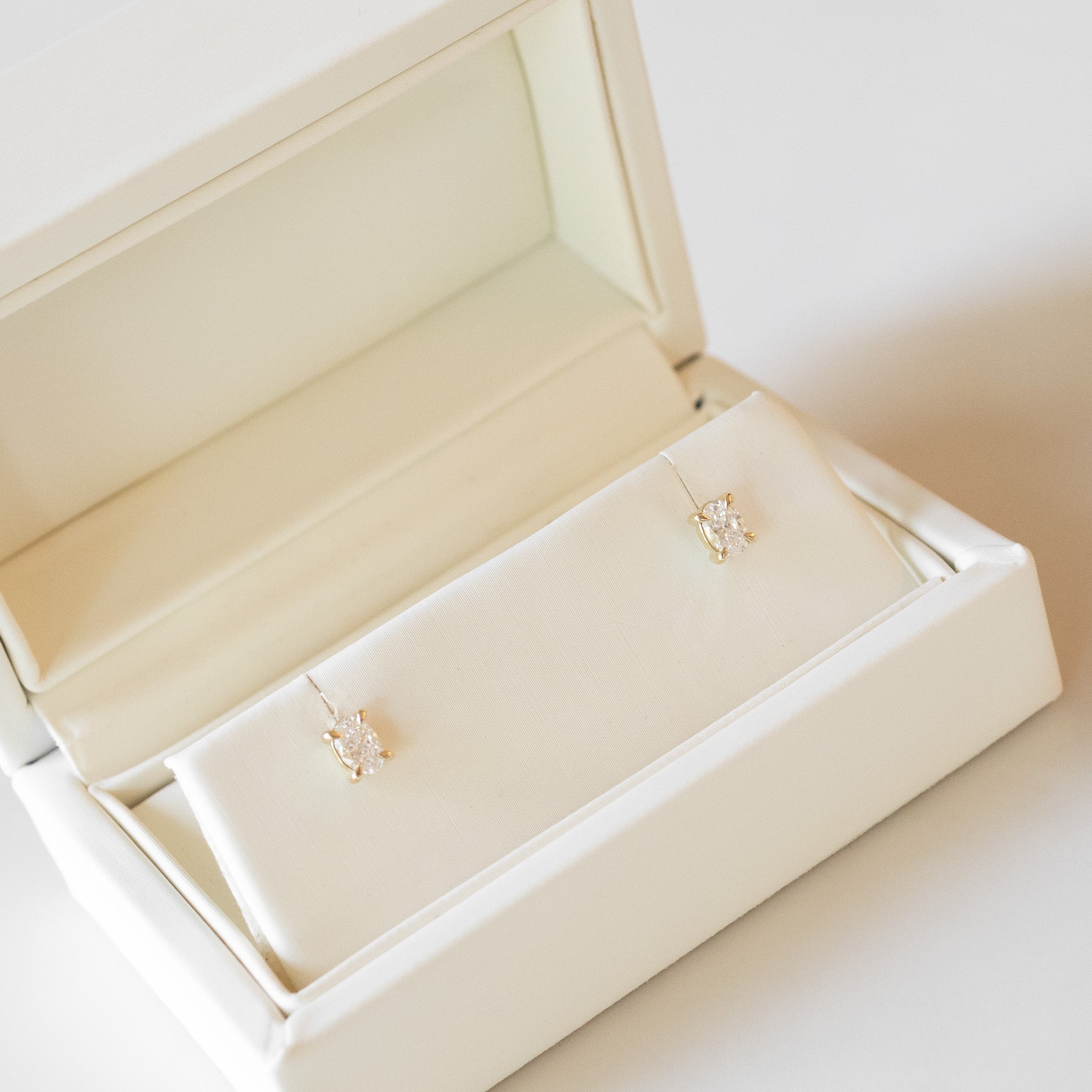 Gold earrings in an open jewelry box on a light background