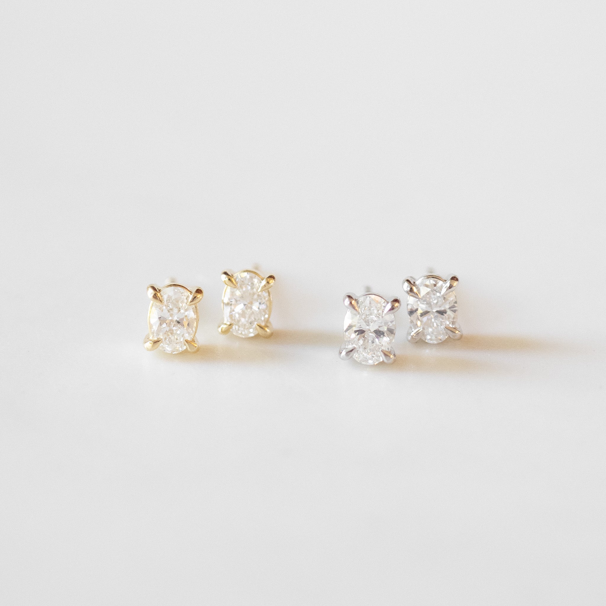 Set of four diamond stud earrings on a light gray background