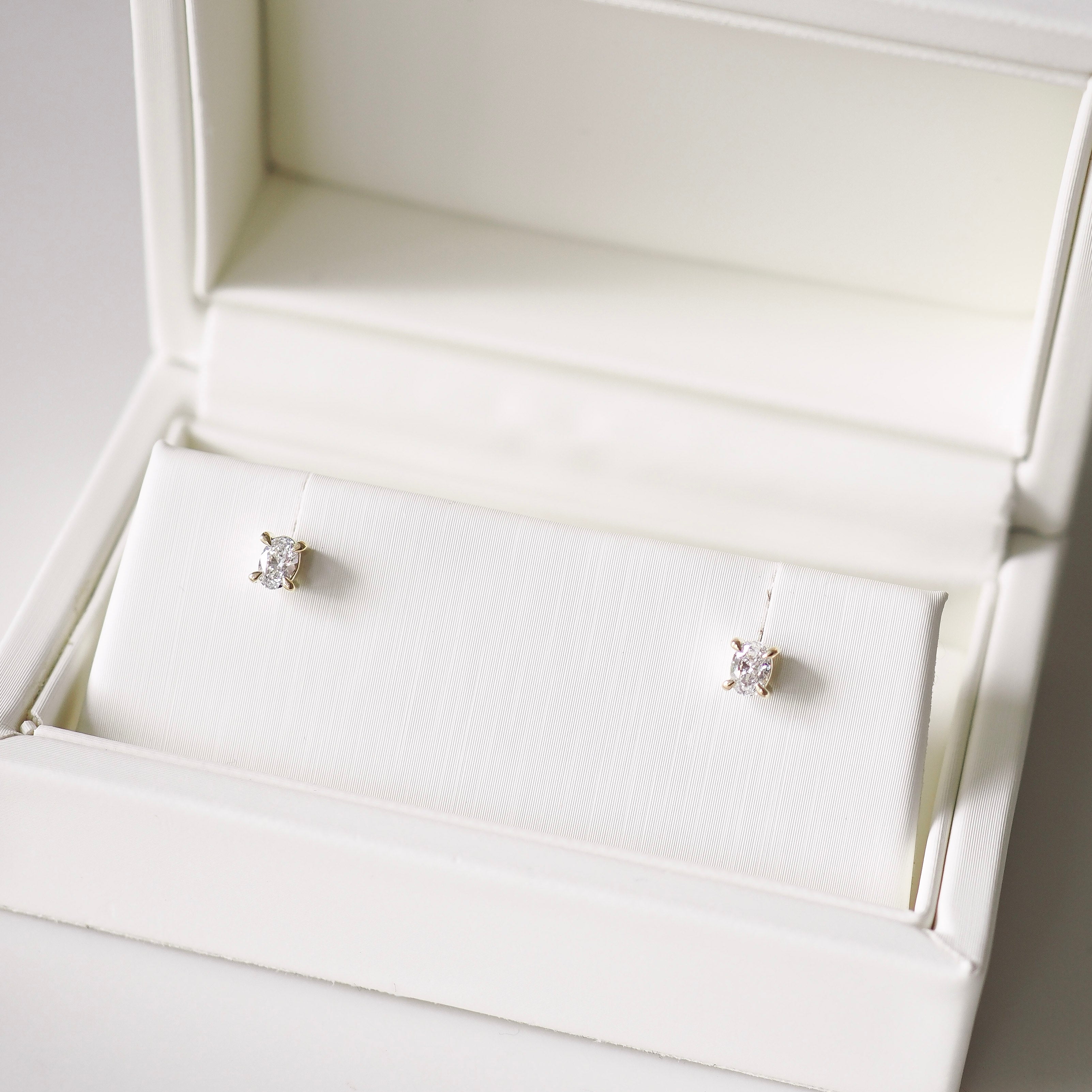 Diamond stud earrings in a white jewelry box