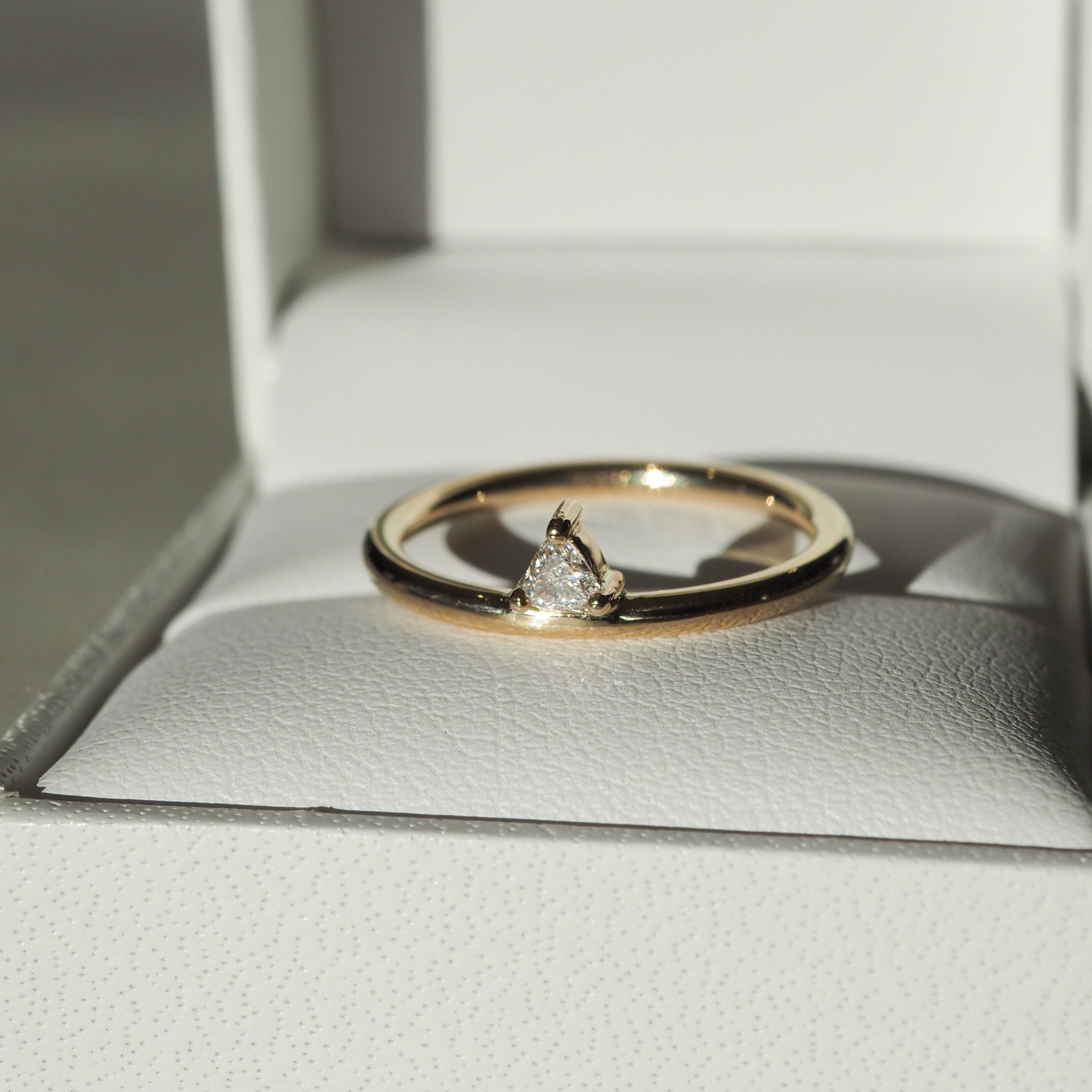 Gold engagement ring with a pear-cut diamond set in a white jewellery box, epitomising luxury and elegance.