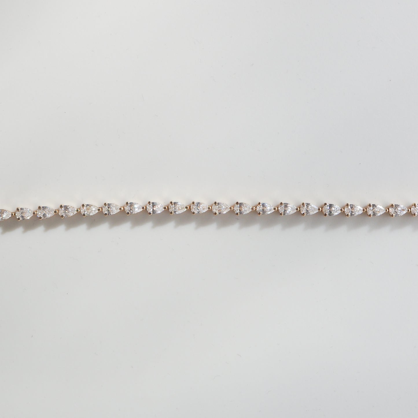 Elegant diamond tennis bracelet on a light background, featuring round diamonds set in a delicate, straight line. Perfect for luxury jewellery lovers.