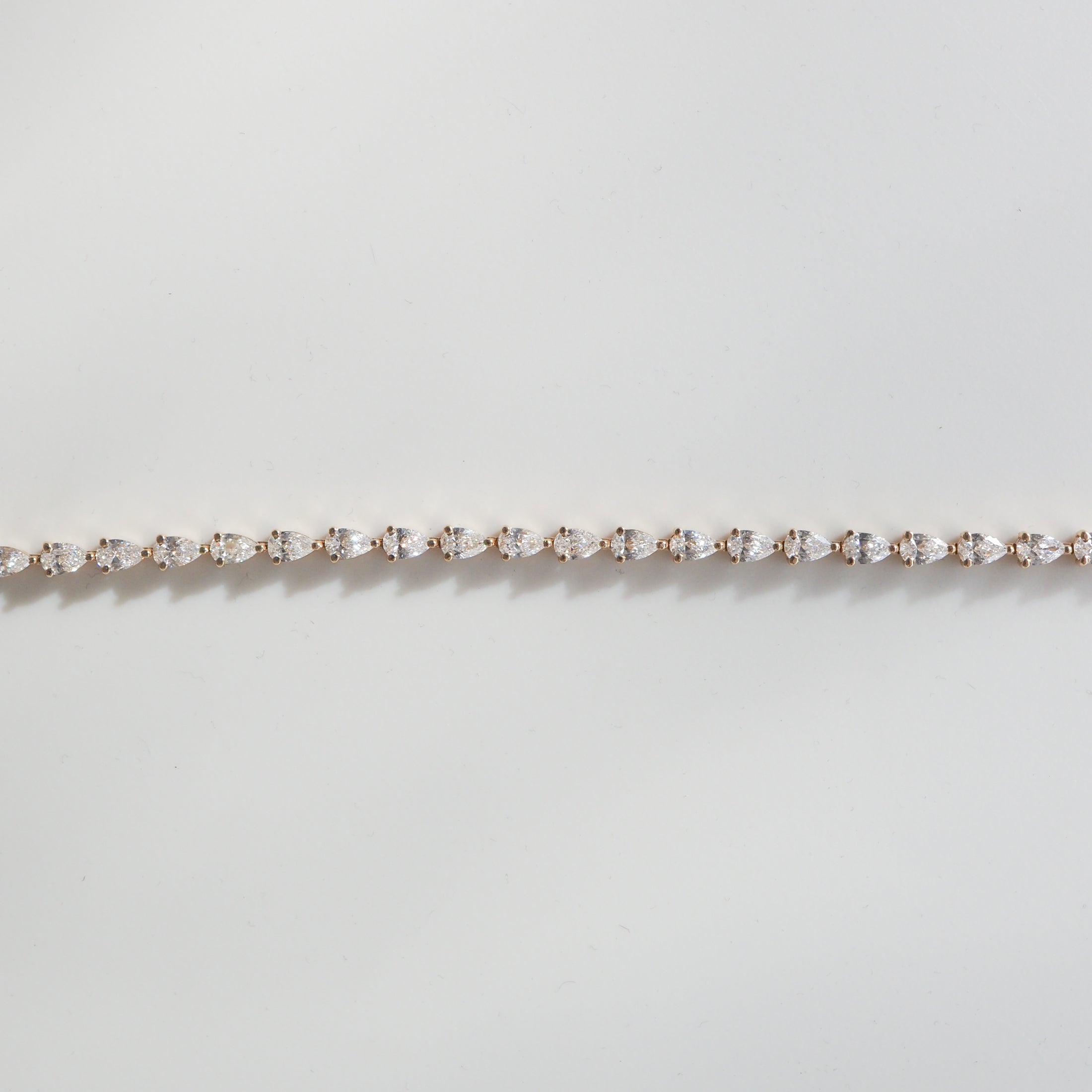 Elegant diamond tennis bracelet on a light background, featuring round diamonds set in a delicate, straight line. Perfect for luxury jewellery lovers.