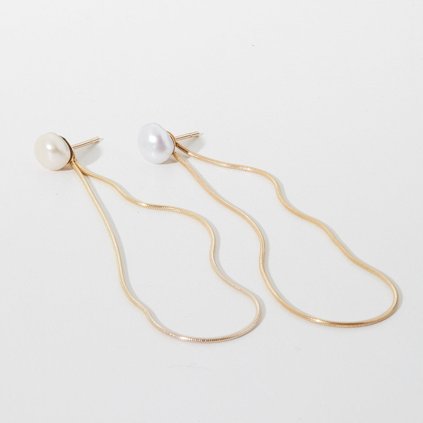 Elegant gold drop earrings with pearl studs, featuring delicate wavy chains. Perfect luxury jewellery piece for stylish sophistication.