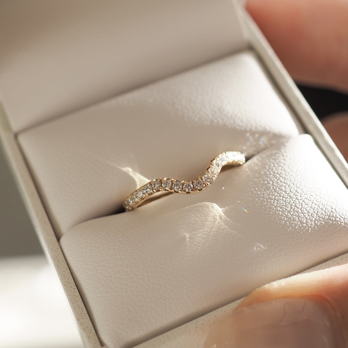 Elegant wavy diamond ring in a white jewellery box, showcasing exquisite craftsmanship and luxury design.