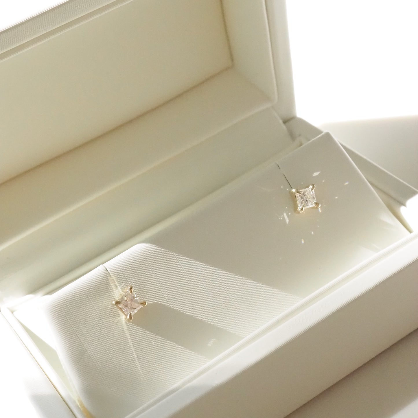 Pair of princess diamond stud earrings in a white jewelry box
