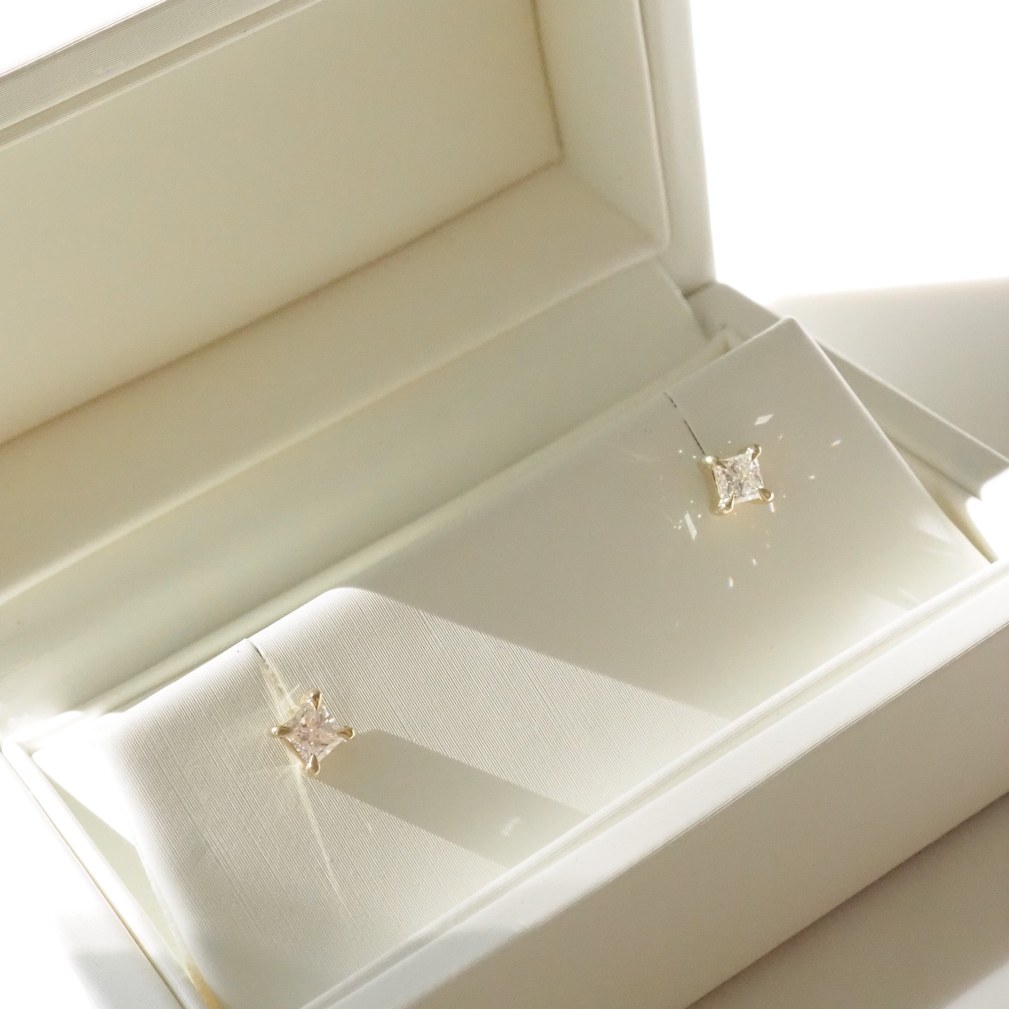Pair of princess diamond stud earrings in a white jewelry box