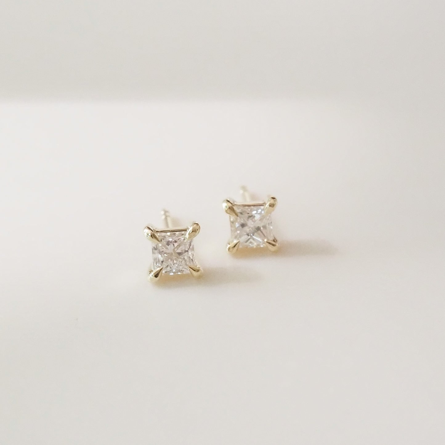 Gold princess earrings with clear gemstones on a light gray background