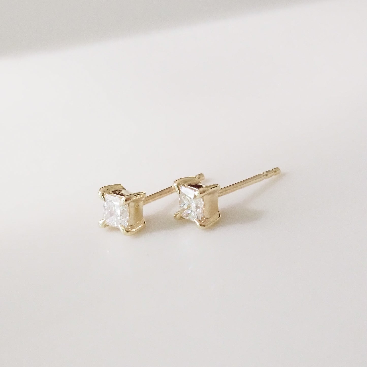 Gold princess earrings with clear gemstones on a light gray background