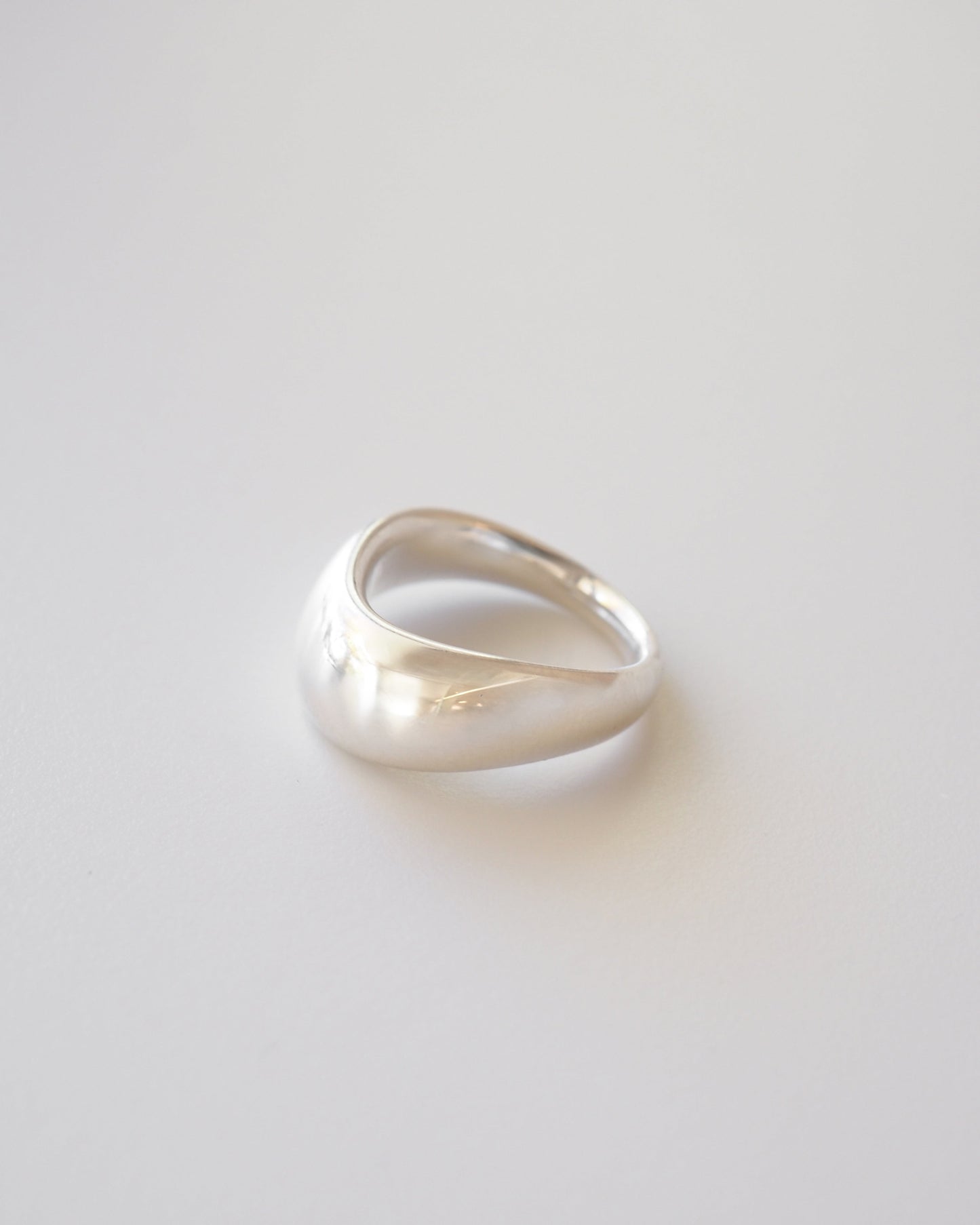 A bold silver curved ring on a white background
