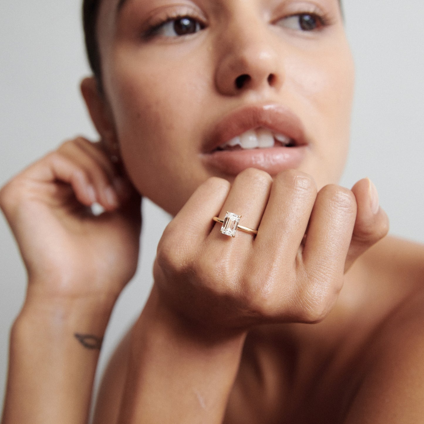 Woman showcasing an emerald-cut diamond ring on her finger, embodying luxury and elegance in high-end jewellery.