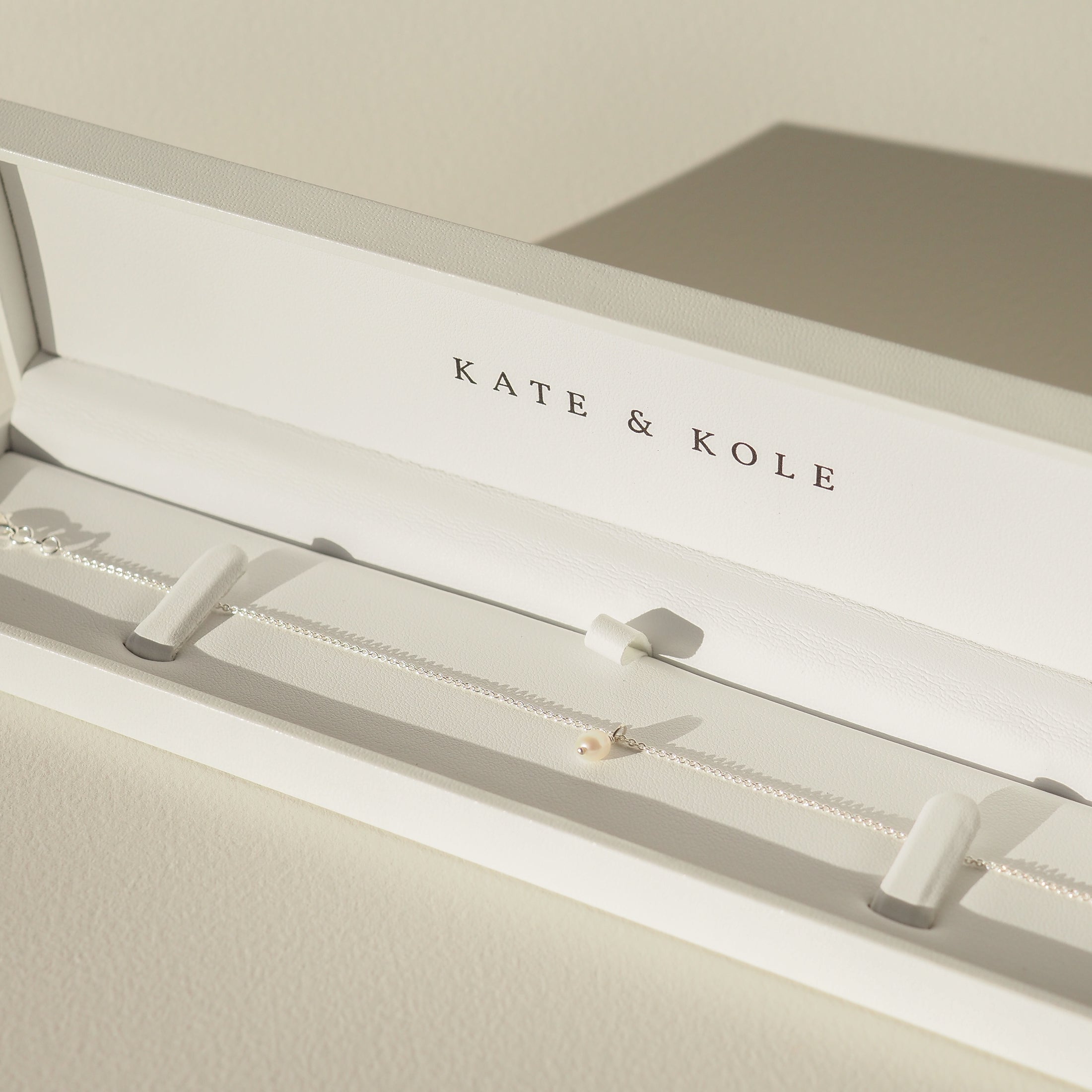 Elegant Kate & Kole necklace in an open white jewellery box, featuring a delicate chain with a single pearl.